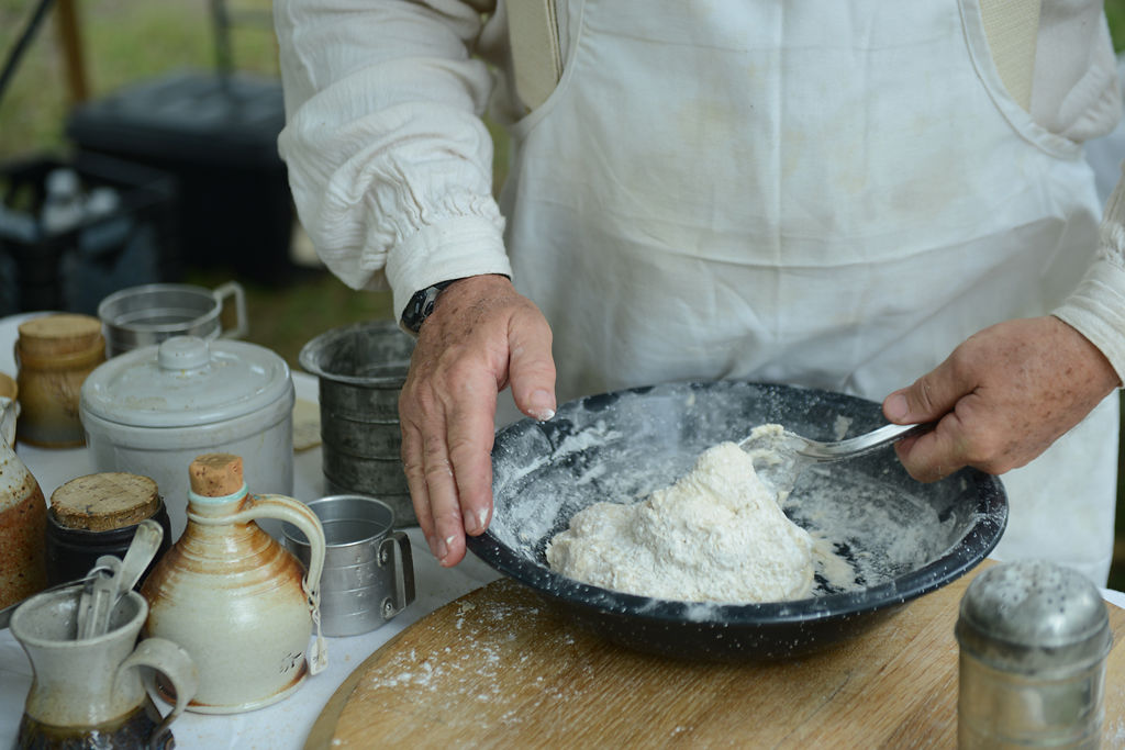 Scott Stager uses a spoon to knead bread dough on Saturday